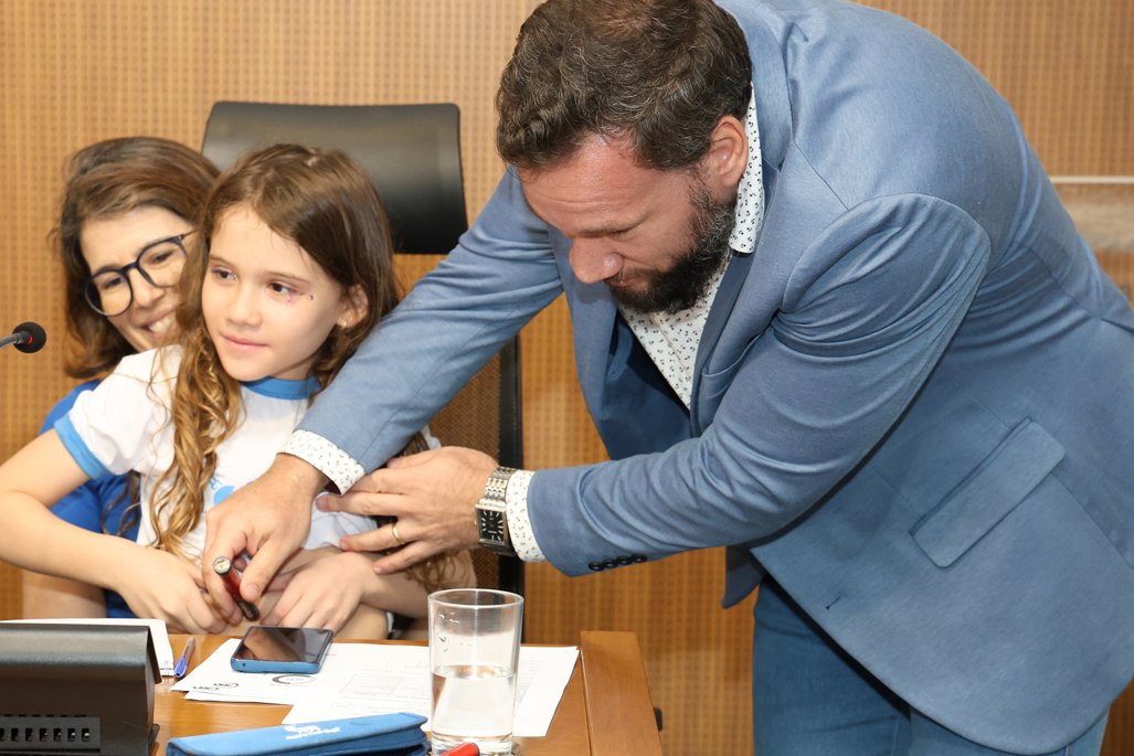 Imagem: Eduarda, 8 anos, recebeu medicamento após alerta do sensor no celular do pai; ambos participaram da audiência na ALEMS